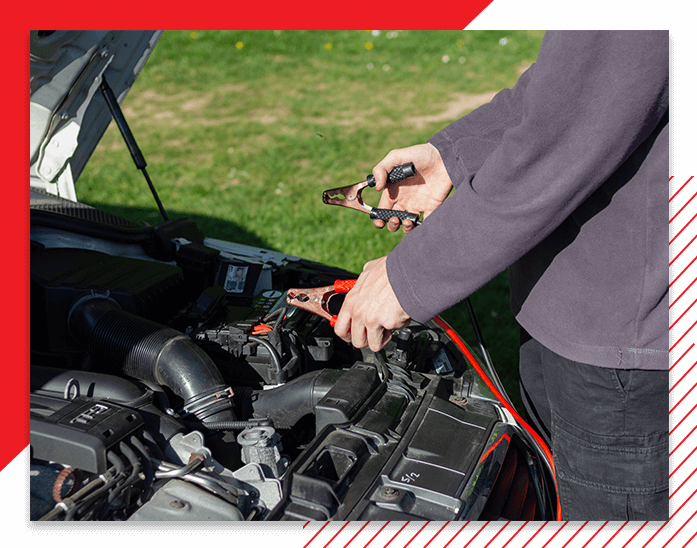 Car mechanic is checking the engine and holding the battery gauge.